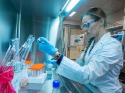 Photo of student using pipette to fill vial in laboratory.