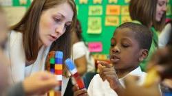 Student teacher works with elementary school student to build a tower